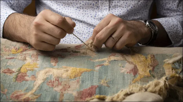 Artisan restaurant une tapisserie ancienne à l'aiguille dans l'atelier ITAO à Paris